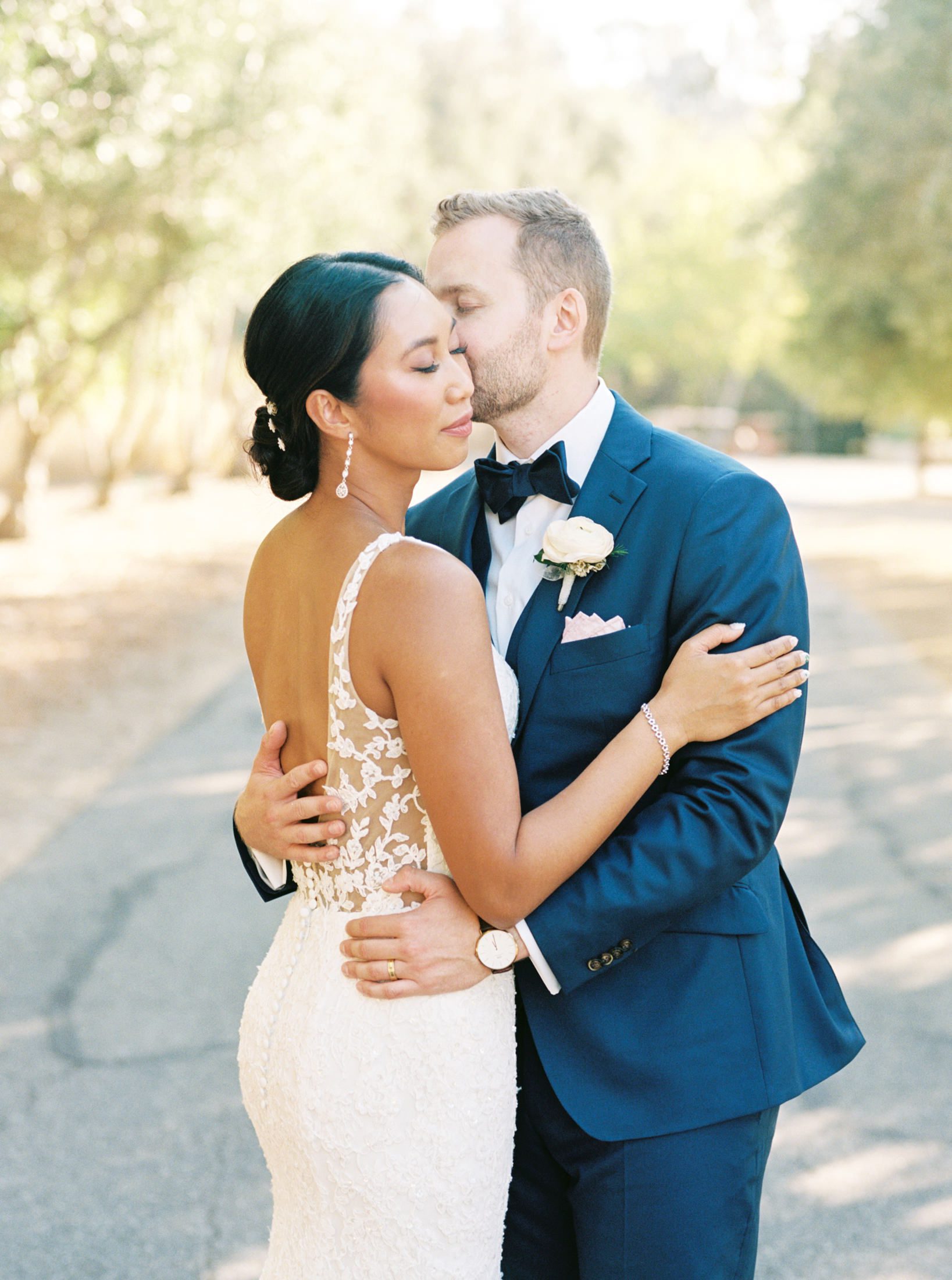 Bride and groom kiss beneath the olive grove at luxurious jewish wedding at San Luis Obispo Wedding Venue Higuera Ranch photographed by Fine Art Film Photographer Tina Loveridge of Loveridge Photography