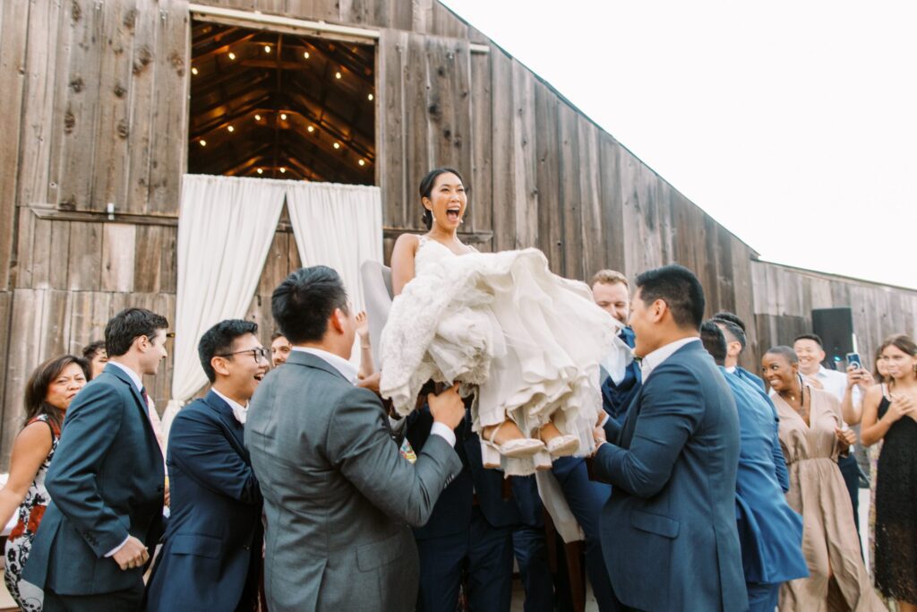 Lifting the bride in chair at luxurious jewish wedding at San Luis Obispo Wedding Venue Higuera Ranch photographed by Fine Art Film Photographer Tina Loveridge of Loveridge Photography