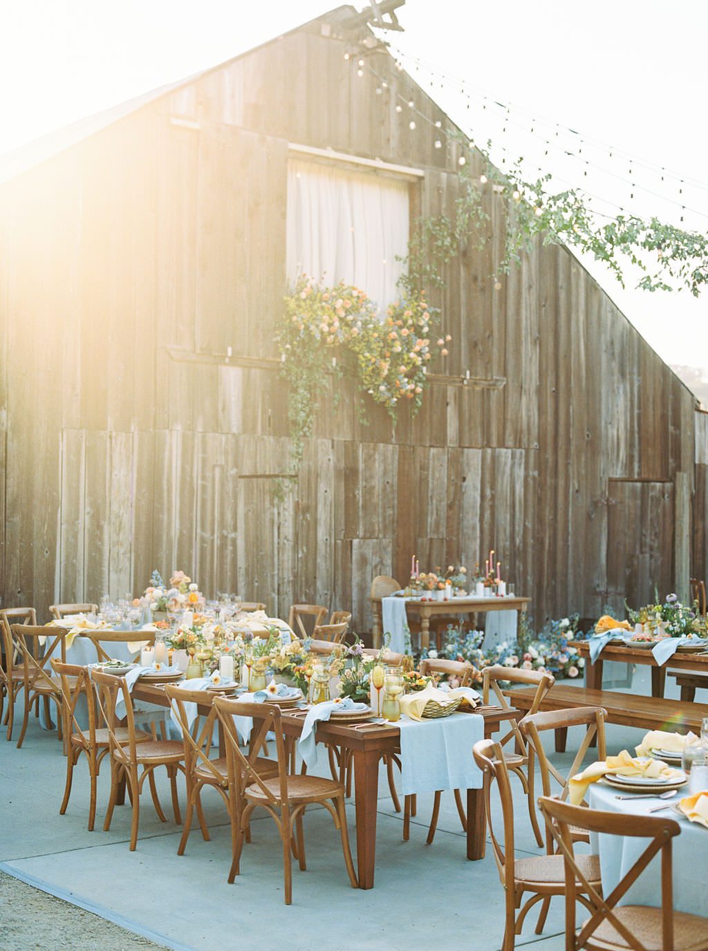 Historic Rustic Barn at Luxury Wedding Venue in San Luis Obispo featuring bistro lights lined with florals over expansive patio for celebration